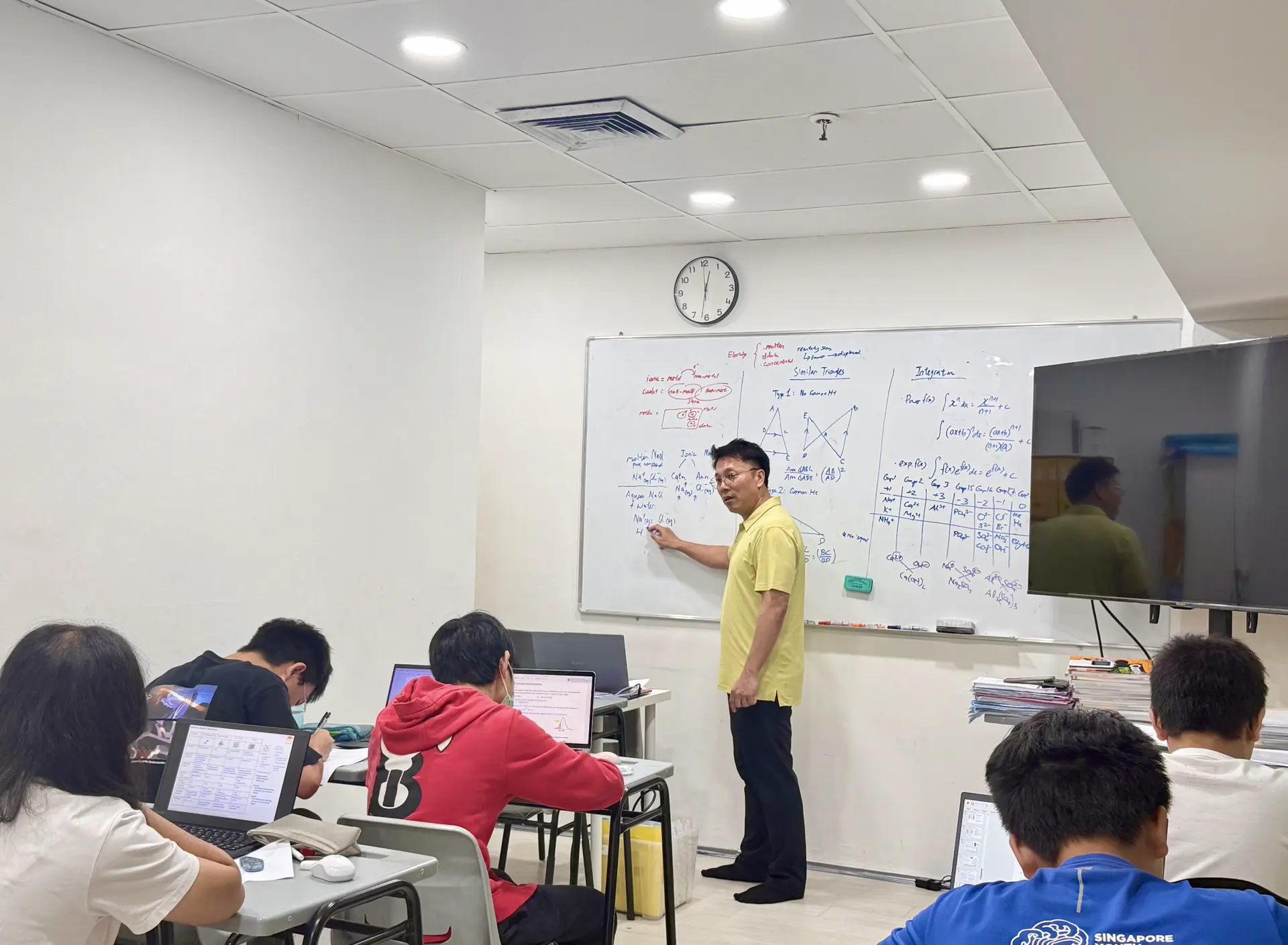 Dave Tan teaching math and science equations on a whiteboard to a small group of students at Gobosh Education